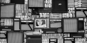 black and white image of old TVs, speakers, and records with a lonely Elvis in the center